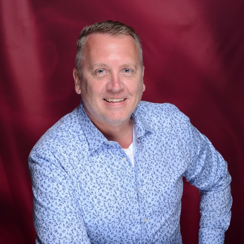 ohn Parkins, Chief People Officer at Big Chalk seen posing for a photo in a blue color shirt